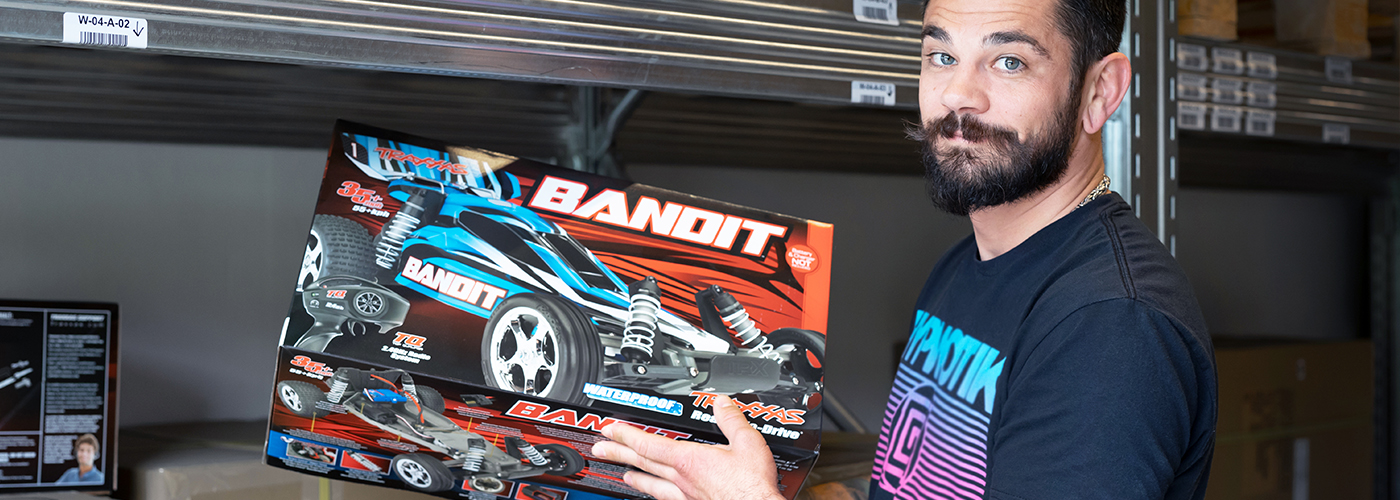 Personal från Rynos som står i ett välfyllt lager och håller i en radiostyrd bil i kartong